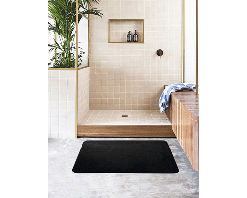 Badezimmer mit ebenerdiger Dusche, Holzbänken und einer schwarzen Badematte