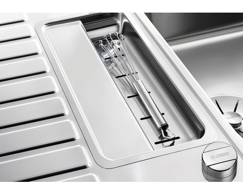 Edelstahlspüle mit Abtropffläche und Schneidbrettmulde, in der ein Schneebesen liegt