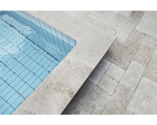 Vue détaillée d''une piscine avec bordure en travertin et dalles de terrasse en travertin