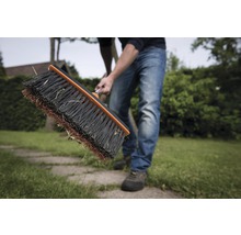 Person kehrt Rasen mit Straßenbesen