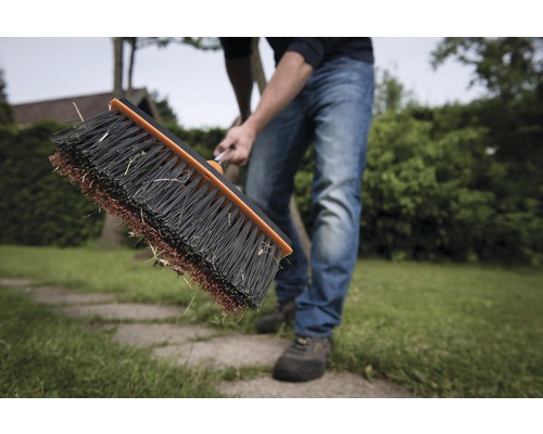 Person kehrt Rasen mit Straßenbesen