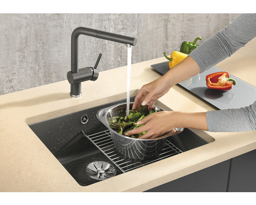 Femme lave de la salade dans un évier de cuisine avec un robinet