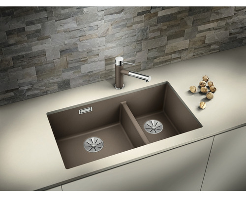 Doppelspüle mit Armatur auf einer Küchentheke vor einer Steinwand