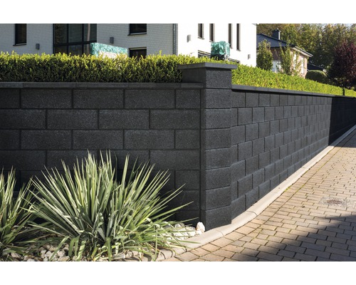 Haut mur de jardin en béton avec piliers et végétation