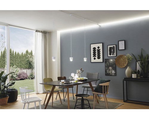 Salle à manger lumineuse avec table, chaises et suspensions sur un rail