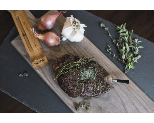 Steak de bœuf avec thermomètre, oignons, ail et thym