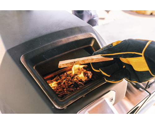 Personne alimentant un four avec du bois en portant des gants