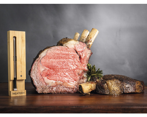 Côte de bœuf rôtie avec os et thermomètre à viande Meater Plus sur une table en bois