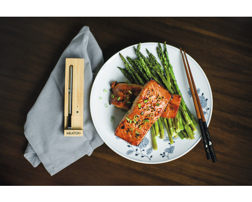 Une assiette de saumon, d''asperges et de baguettes à côté d''un thermomètre à viande intelligent