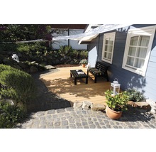 Espace jardin avec terrasse en bois, banc et table devant un chalet de jardin
