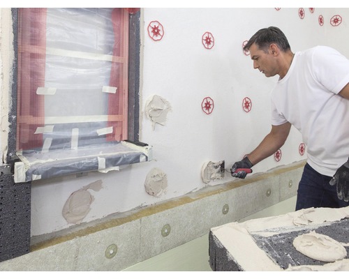 Fassadendämmung mit einem Mann bei der Arbeit mit einer Kelle.