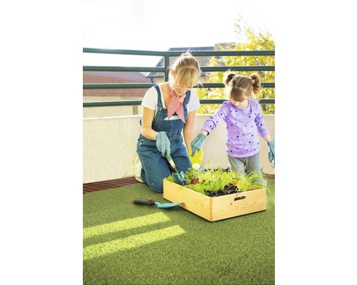 Une mère et sa fille jardinent ensemble dans une jardinière surélevée sur un balcon