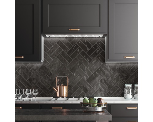 Küchenszene mit dunklen Schränken, Fischgrätenmuster-Fliesen und Küchenutensilien