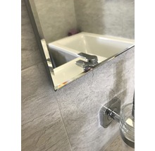 Gros plan d'un miroir dans une salle de bains reflétant une baignoire et un robinet.