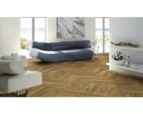 Wohnzimmer mit Fischgrätparkett, Sofa und Regalen.