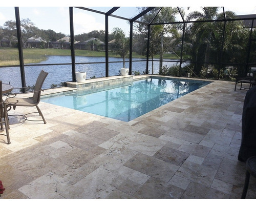 Schwimmbad mit Steinboden und umgebender Terrasse unter einem schwarzen Netz