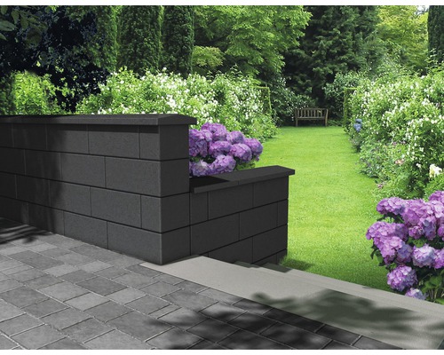 Gartenlandschaft mit einer Mauer aus Betonsteinen und Blumenbeeten