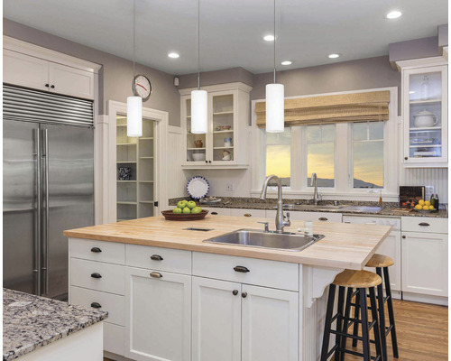 Helle Küche mit Kücheninsel, Spüle, Wasserhahn und Sitzgelegenheiten.