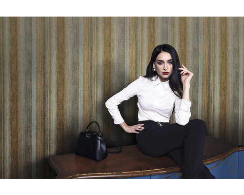 Frau sitzt auf einem Schrank vor einer gestreiften Tapete