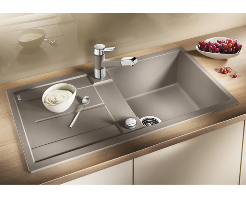 Spüle mit Abtropffläche und Küchenarmatur auf einer Arbeitsplatte mit Speisen.