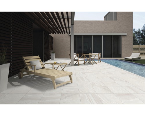 Terrasse avec carrelage, chaise longue, table et chaises à côté d''une piscine.