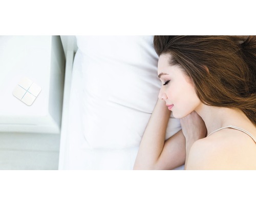Frau schläft im Bett mit Smart Home Schalter auf dem Nachttisch