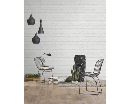 Helle Raumansicht mit Backsteinwand, Pendelleuchten, Stühlen, Tischleuchte und Dekorationen