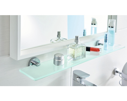 Salle de bains avec miroir, étagère en verre et divers articles de bain