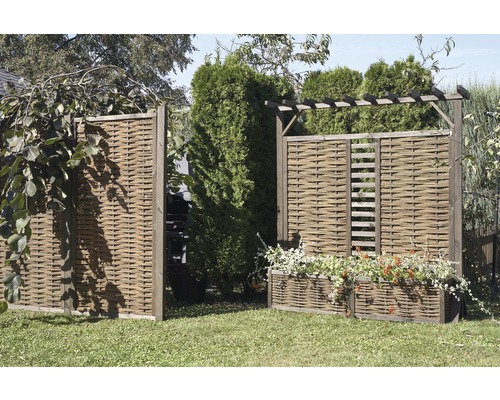 Gartenszene mit geflochtenen Sichtschutzzäunen und bepflanzten Kästen