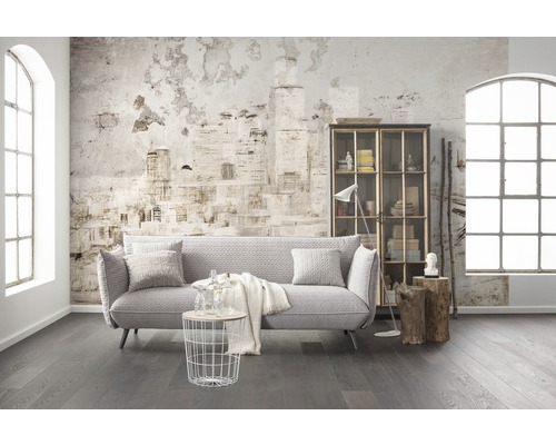 Wohnzimmer mit Sofa, Regal, Tisch und Dekor vor einer Wand mit Zeitungsmuster