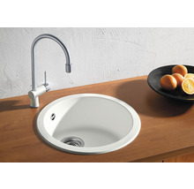 Rundes Spülbecken mit Wasserhahn auf einer Holzoberfläche.