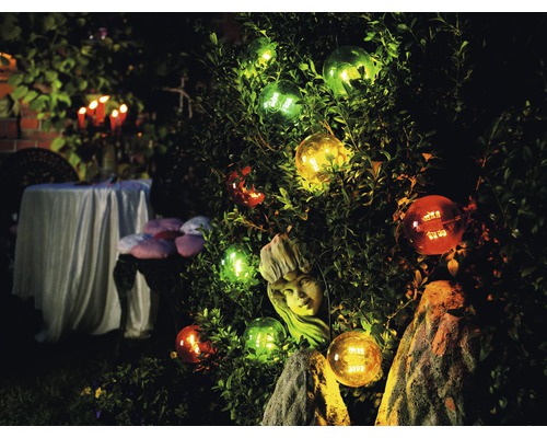 Jardin décoré avec des sphères illuminées et une sculpture dans les buissons