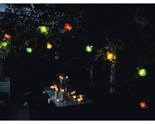 Table de jardin éclairée avec guirlande lumineuse décorative à l''extérieur.