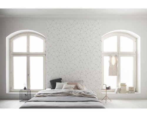 Chambre avec papier peint géométrique, lit et fenêtres