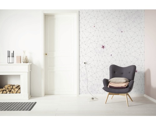 Salon lumineux avec cheminée, fauteuil et papier peint géométrique