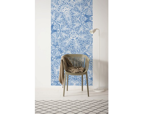 Raum mit einer gemusterten Tapete, einem Stuhl, einer Decke, einer Stehlampe und einem Teppich