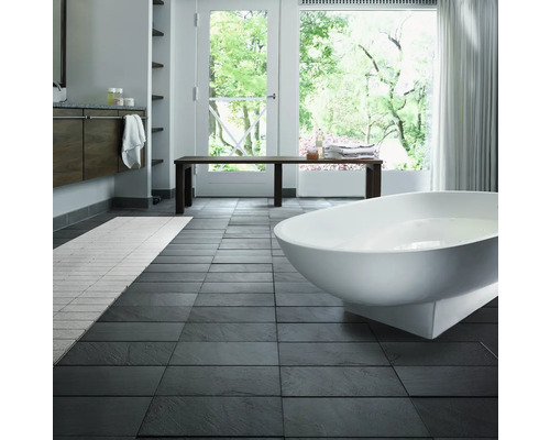 Salle de bain lumineuse avec baignoire, banc et carrelage foncé