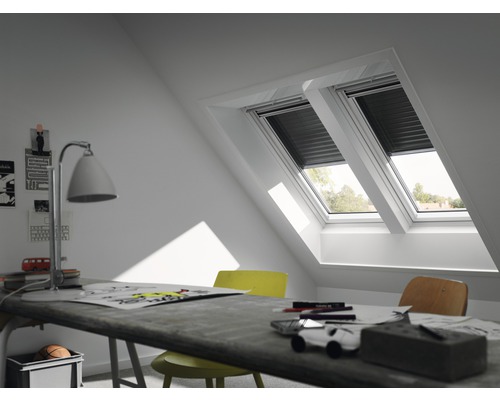 Deux fenêtres de toit avec volets roulants dans une chambre mansardée avec bureau