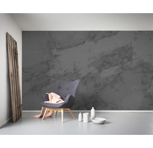 Ein Zimmer mit einem grauen Sessel, einer grauen Mustertapete und dekorativen Elementen.