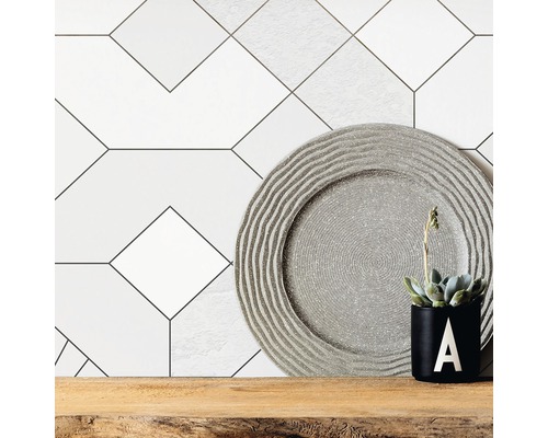 Carreaux muraux décoratifs avec motif géométrique, assiette décorative et plante en pot sur étagère en bois.