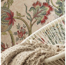 Vue détaillée d''une pièce avec du papier peint à motifs, un fauteuil et une couverture.