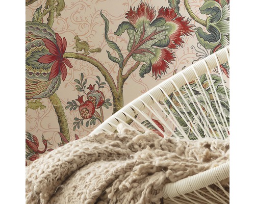 Vue détaillée d''une pièce avec du papier peint à motifs, un fauteuil et une couverture.