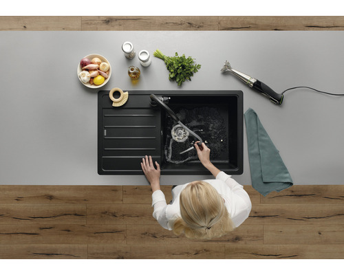 Spüle mit Abtropffläche auf einer Arbeitsplatte mit Lebensmitteln und einem Stabmixer, Draufsicht.