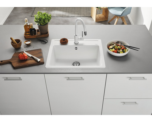 Küchenspüle mit Armatur auf einer Küchentheke mit Gemüse und Küchenutensilien