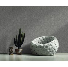 Innenraum mit gepolstertem Sessel, Kaktus im Topf und gemusterter Wand