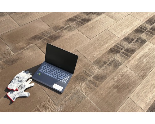 Verlegung von Bodenfliesen in Holzoptik mit Laptop und Arbeitshandschuhen