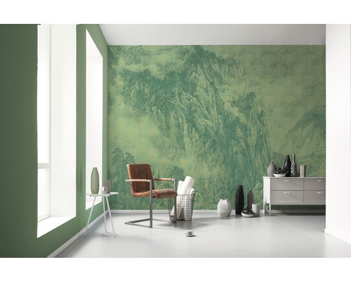 Espace de vie avec papier peint vert à motif de montagne, fauteuil et commode