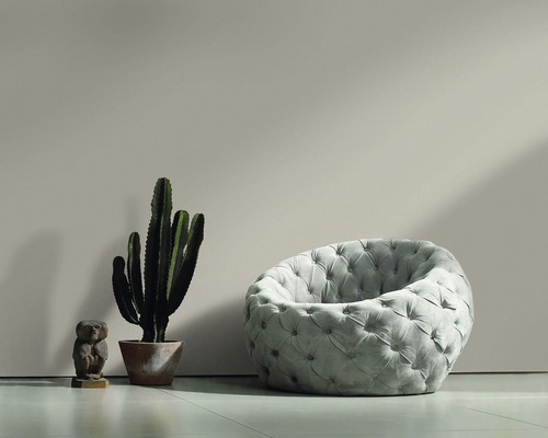 Fauteuil gris avec boutons rembourrés à côté d''un cactus et d''une figurine décorative