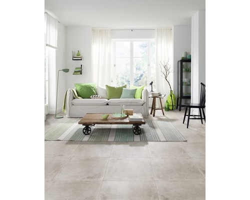 Heller Wohnraum mit Fliesenboden, Sofa, Couchtisch und dekorativen Elementen.