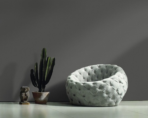 Fauteuil oreille gris avec capitonnage, cactus et figurine en bois